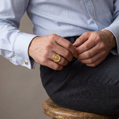 18k gold Saint Michael archangel signet ring on a man's hand with gold cufflinks