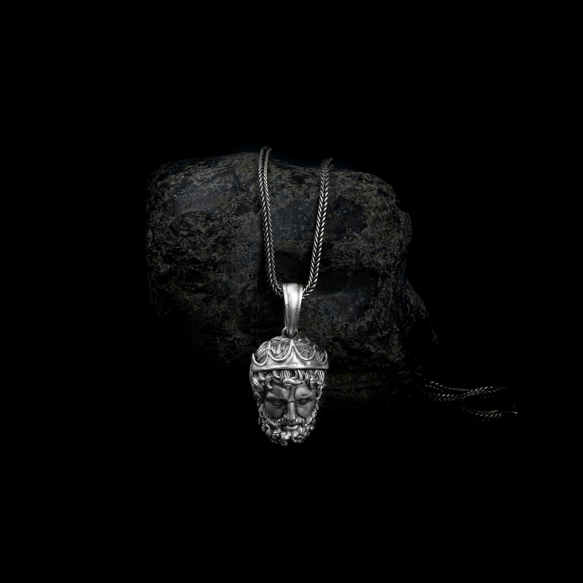 Sterling silver pendant necklace showcasing a detailed carving of Poseidon's face, adorned with a crown and accentuated by intricately designed hair and beard.